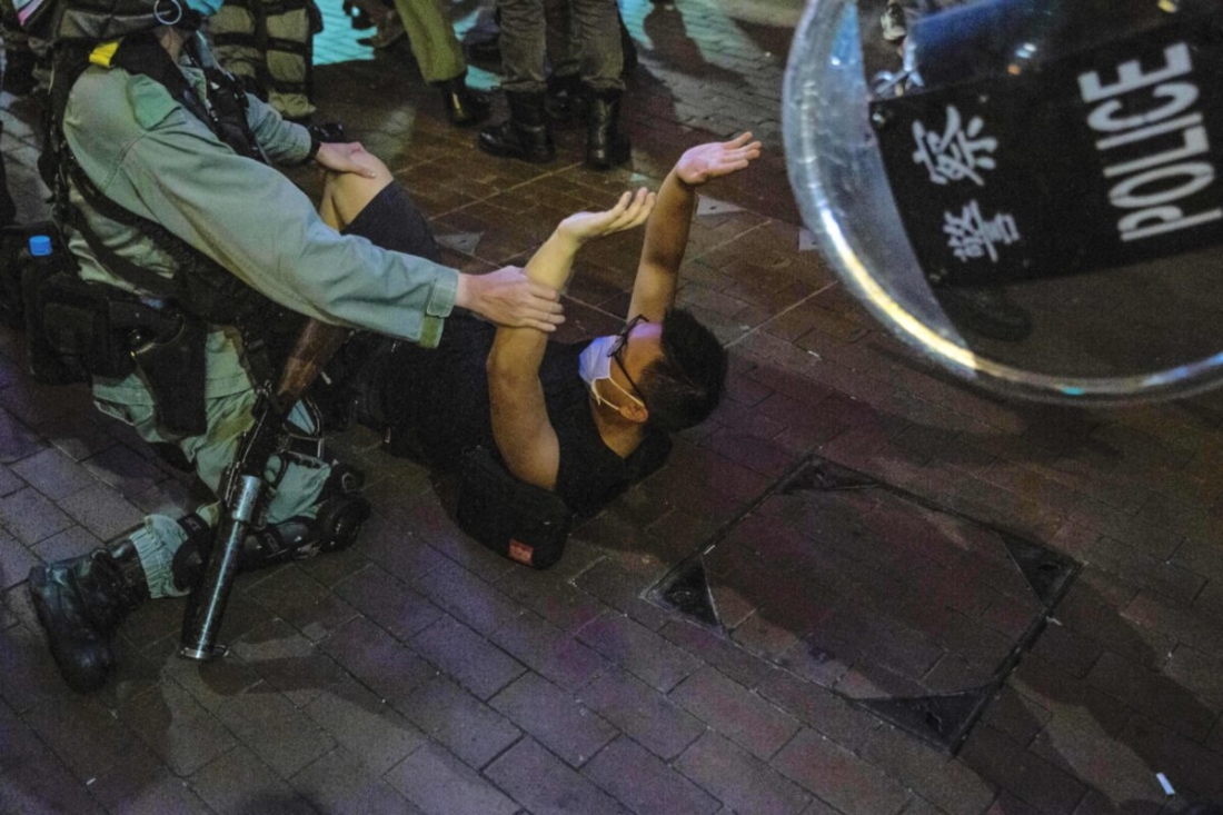 Một sĩ quan cảnh sát (trái) bắt giữ một người đàn ông (giữa) khi đoàn người biểu tình tập trung tại quận Mong Kok của Hong Kong vào ngày 12/6/2020. (Isaac Lawrence / AFP / Getty Images)