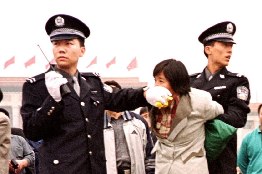Hai sĩ quan cảnh sát Trung Quốc bắt giữ một học viên Pháp Luân Đại Pháp tại Quảng trường Thiên An Môn ở Bắc Kinh vào ngày 10/1/2000. (Chien-Min Chung / Ảnh AP)