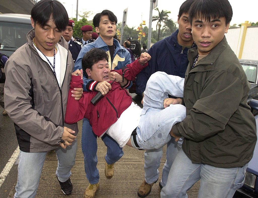 4 công an mặc thường phục đang bắt giữ một học viên Pháp Luân Công vào ngày 20/12/2000, ở MaCau - Trung Quốc.