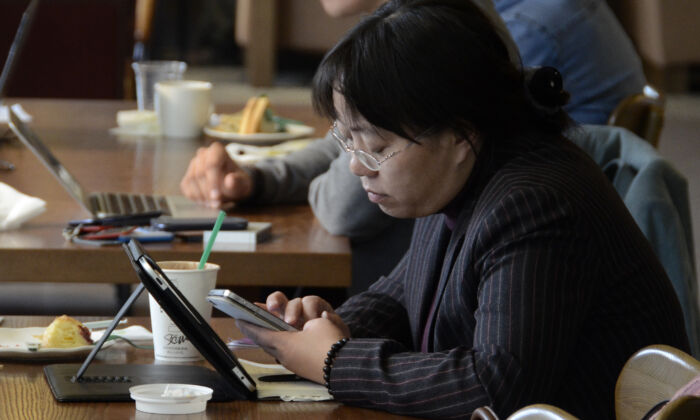Một phụ nữ xem điện thoại và máy tính bảng trong một quán cà phê ở Bắc Kinh vào ngày 2/11/2012. (Ảnh Wang Zhao/ AFP qua Getty Images)
