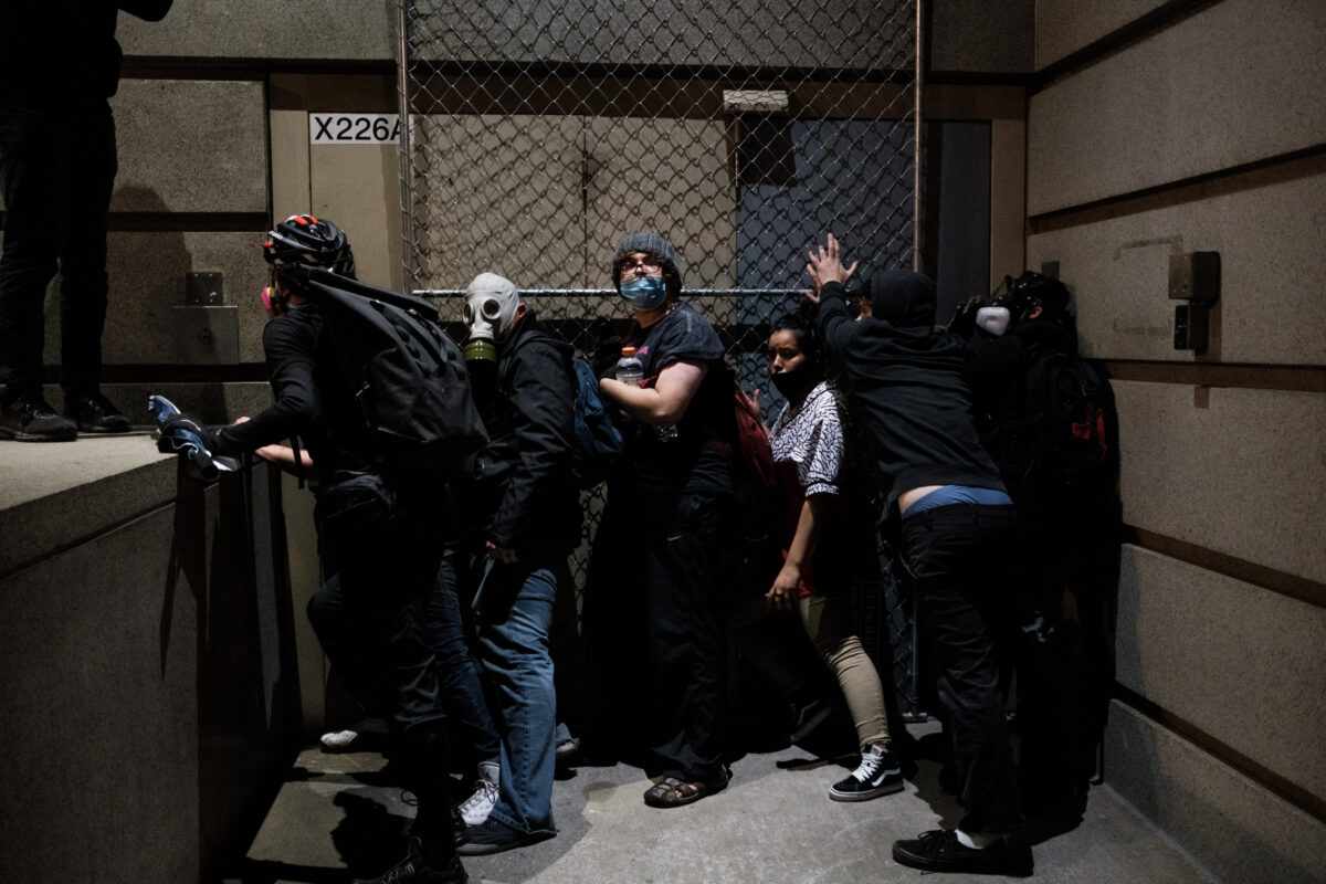 Những kẻ bạo loạn cố gắng chặn một cánh cửa dẫn đến Trung tâm Tư pháp Hạt Multnomah ở Portland, Ore., vào ngày 17/7/2020. (Ảnh Mason Trinca/ Getty Images)