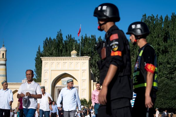 Cảnh sát đang tuần tra khi những người Hồi giáo rời khỏi Nhà thờ Hồi giáo Id Kah sau buổi cầu nguyện buổi sáng trong ngày lễ Eid al-Fitr ở Kashgar, Tân Cương, vào ngày 26/6/2017. (Ảnh Johannes Eisele / AFP / Getty Images)