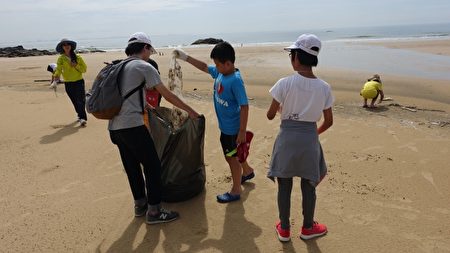 Các bạn nhỏ tham gia vào hoạt động làm sạch bãi biển. (Giản Nguyên Lương / Epoch Times)