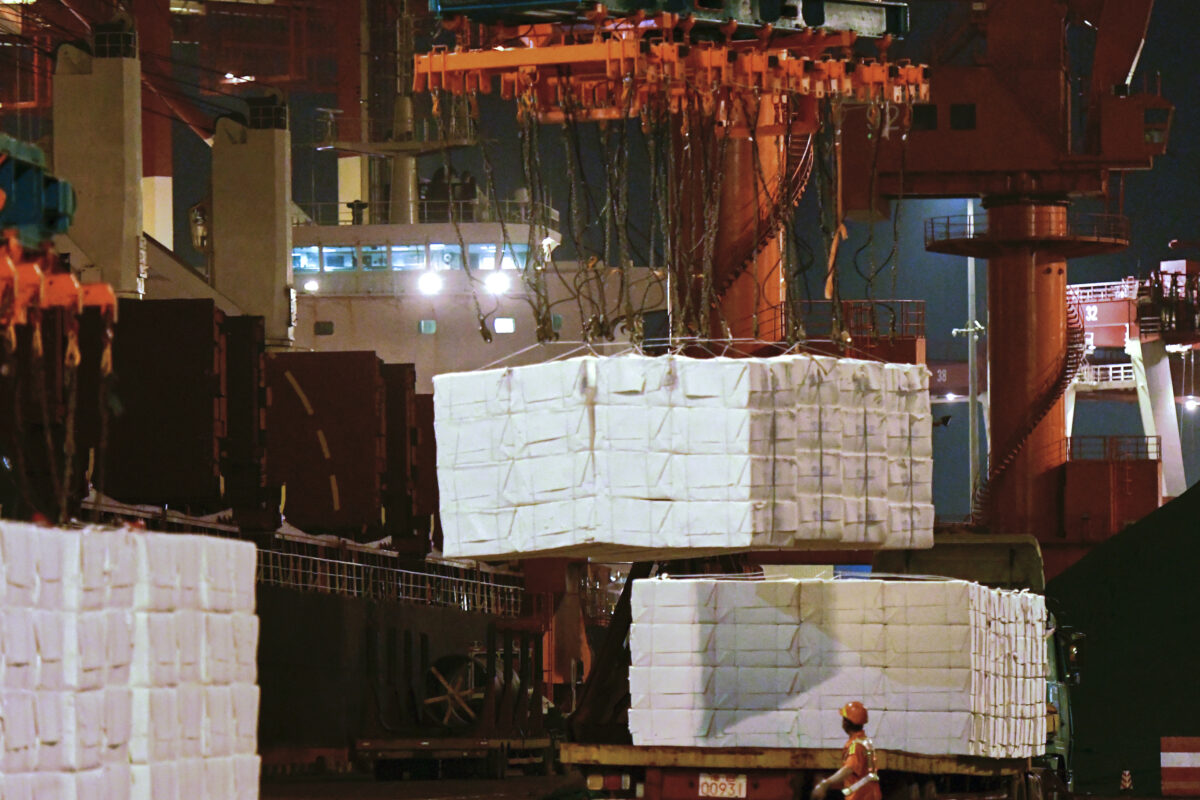 Một công nhân quan sát một chiếc máy đang tải hàng hóa lên tàu container tại một xưởng đóng tàu ở Thanh Đảo thuộc tỉnh Sơn Đông, miền đông Trung Quốc vào ngày 25 tháng 9 năm 2020. (Ảnh Chinatopix / AP)