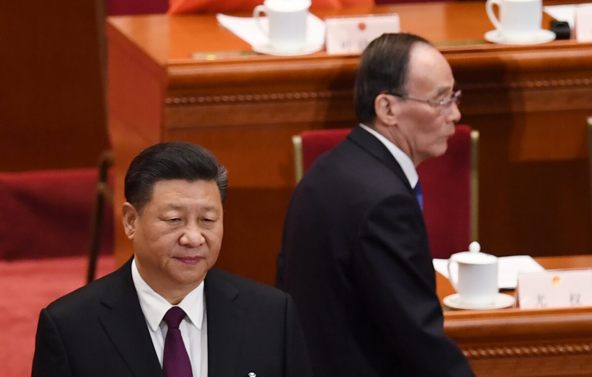 Lãnh đạo Trung Quốc Tập Cận Bình (trái) đứng trong khi ông Vương Kỳ Sơn (phải), cựu Bí thư Ủy ban Kiểm tra Kỷ luật Trung ương, đến dự phiên họp đầu tiên của Đại hội Đại biểu Nhân dân Toàn quốc lần thứ 13 của Đảng Cộng sản Trung Quốc tại Bắc Kinh, Trung Quốc, vào ngày 17/3/2018. (Ảnh Greg Baker/ AFP qua Getty Images)
