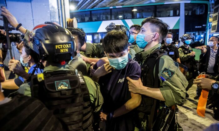 Một cảnh sát chống bạo động (phải) bắt giữ một người đàn ông (ở giữa) trong cuộc biểu tình của các Ủy viên Hội đồng quận tại một trung tâm mua sắm ở Yuen Long, Hồng Kông vào ngày 19 tháng 7 năm 2020. (Ảnh Isaac Lawrence / AFP qua Getty Images)