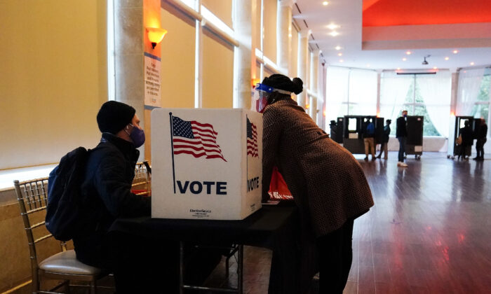 Một nhân viên phòng phiếu nói chuyện với một cử tri trước khi họ bỏ phiếu trên một lá phiếu giấy ở Georgia. (Ảnh: Brynn Anderson/AP Photo)
