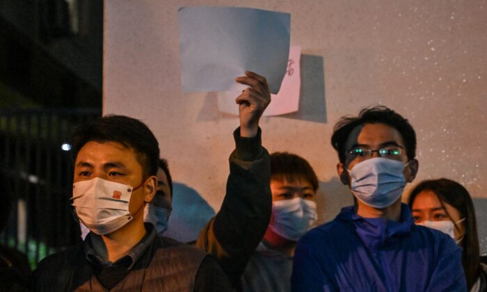 Mọi người giơ lên những tờ giấy trắng như một cách để phản đối, tập trung trên một con đường ở Thượng Hải hôm 27/11/2022, nơi các cuộc biểu tình phản đối chính sách zero COVID của Trung Quốc diễn ra vào đêm trước khi xảy ra vụ hỏa hoạn gây tử vong ở Urumqi, thủ phủ của vùng Tân Cương. (Ảnh: Hector Retamal/AFP qua Getty Images)