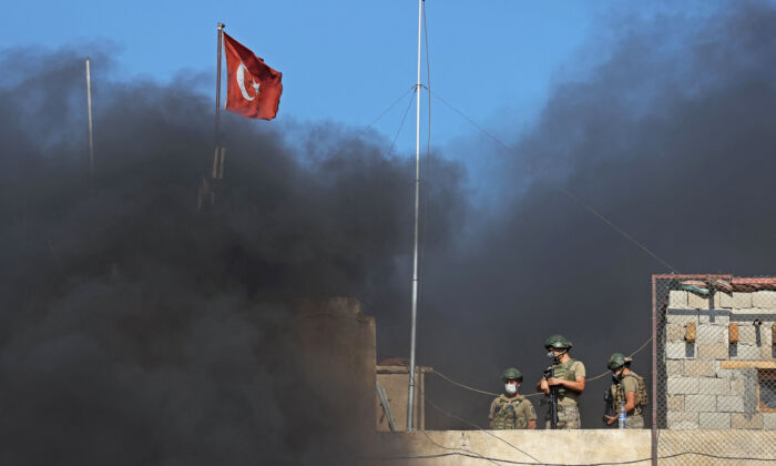 Các binh sĩ Thổ Nhĩ Kỳ đứng gác trên đỉnh một tiền đồn khi khói bốc lên trong một cuộc biểu tình phản đối việc Ankara không hành động trước các cuộc tấn công mới nhất của chế độ Syria ở tỉnh Idlib phía tây bắc Syria hôm 22/07/2021. (Ảnh: Omar Haj Kadour/AFP qua Getty Images)