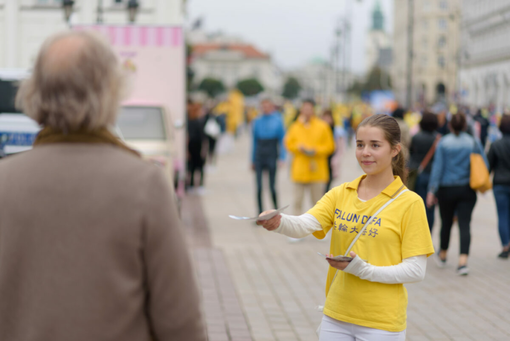Một cô gái phát tờ thông tin trong cuộc diễn hành do các học viên Pháp Luân Đại Pháp tổ chức tại khu trung tâm của Warsaw, Ba Lan, hôm 09/09/2022. (Ảnh: Mihut Savu/The Epoch Times)