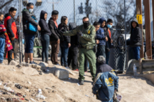 Một nhân viên Tuần tra Biên giới Hoa Kỳ hướng dẫn những người nhập cư đã vượt qua Rio Grande vào El Paso, Texas, hôm 19/12/2022 khi nhìn từ Ciudad Juarez, Mexico. (Ảnh: John Moore/Getty Images)
