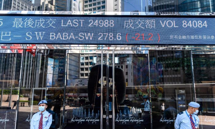 Hoạt động chứng khoán của Alibaba Group Holding Ltd. (BABA-SW) (trên cùng ở giữa) được hiển thị phía trên các nhân viên bảo vệ khi họ đứng bên ngoài tòa tháp Exchange Square ở Hồng Kông vào ngày 04/11/2020. (Ảnh: Anthony Wallace/AFP qua Getty Images)