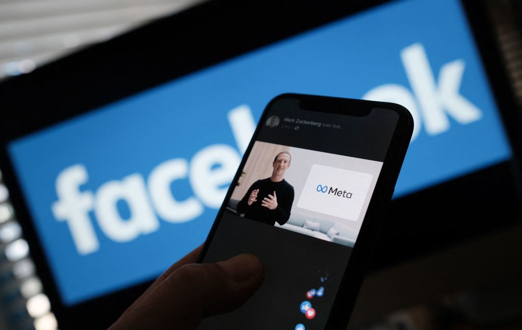 Trong bức hình minh họa được chụp ở Los Angeles vào ngày 28/10/2021 này, một người đang xem Giám đốc điều hành Facebook Mark Zuckerberg tiết lộ biểu tượng META trên điện thoại thông minh. (Ảnh: Chris Delmas/AFP qua Getty Images)