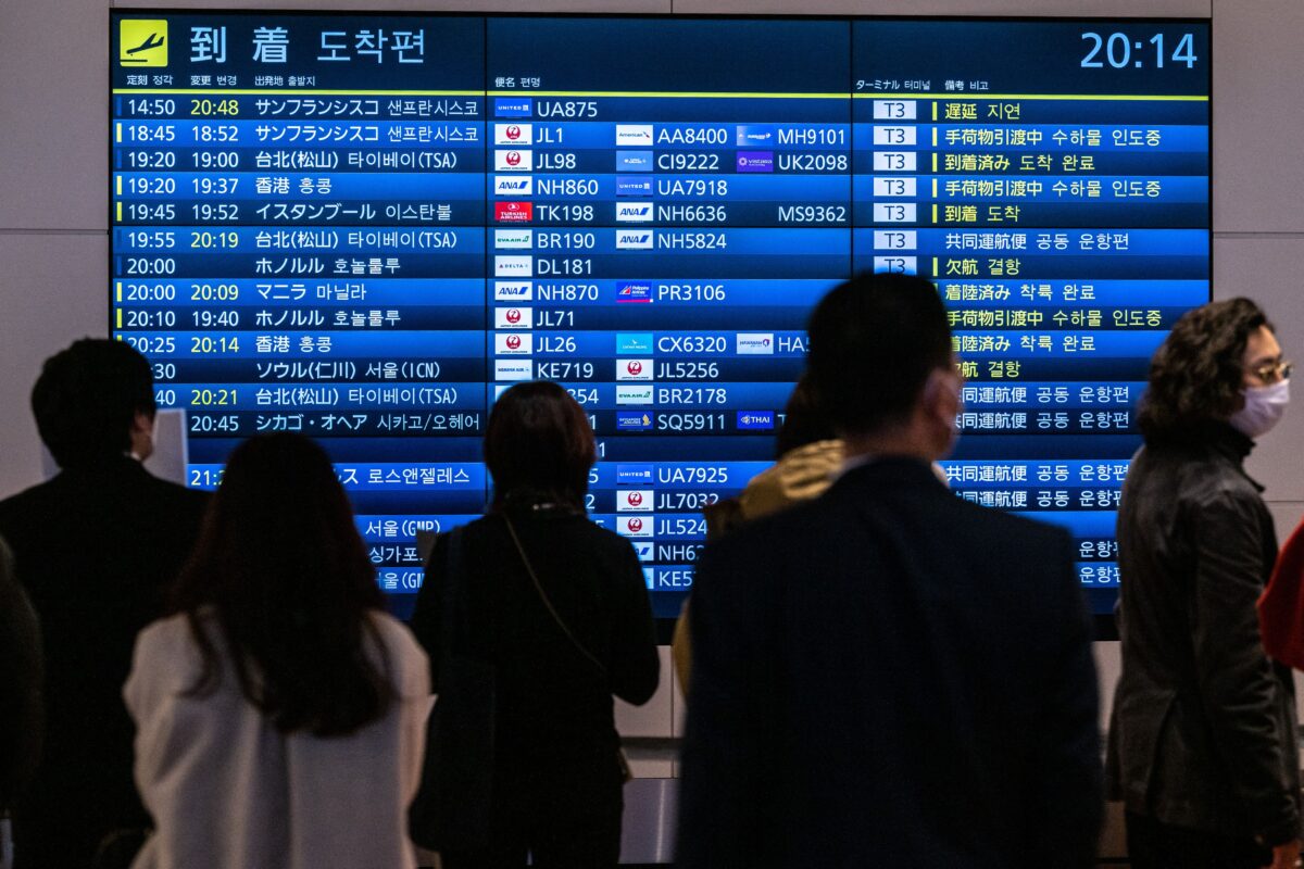 Mọi người chờ đợi trước bảng hiển thị các chuyến bay quốc tế đến tại phi trường quốc tế Haneda của Tokyo hôm 28/12/2022. (Ảnh: Philip Fong/AFP qua Getty Images)