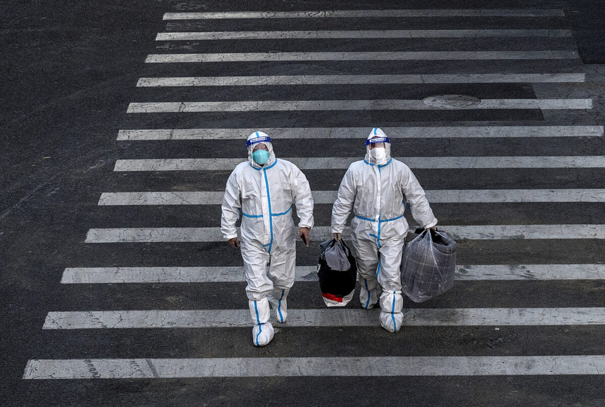 Nhân viên kiểm soát dịch bệnh mặc đồ bảo hộ cá nhân (PPE) để ngăn chặn sự lây lan của COVID-19 khi họ băng qua đường để thực hiện xét nghiệm acid nucleic tại một khu vực có các cộng đồng bị phong tỏa ở Bắc Kinh, Trung Quốc hôm 01/12/2022. (Ảnh: Kevin Frayer/Getty Images)