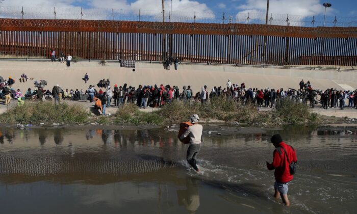 Những người nhập cư bất hợp pháp đi qua sông Rio Grande để đầu hàng các nhân viên Lực lượng Tuần tra Biên giới Hoa Kỳ ở El Paso, Texas, nhìn từ Ciudad Juarez, tiểu bang Chihuahua, Mexico, hôm 13/12/2022. (Ảnh: Herika Martine/AFP via Getty Images)