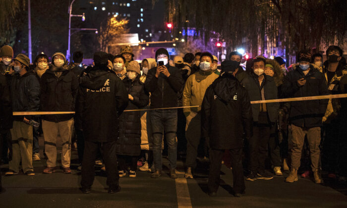 Cảnh sát giữ một số người biểu tình đằng sau một sợi dây trong một cuộc biểu tình phản đối các biện pháp hà khắc của chính quyền Trung Quốc tại Bắc Kinh, Trung Quốc, hôm 27/11/2022. (Ảnh: Kevin Frayer/Getty Images)