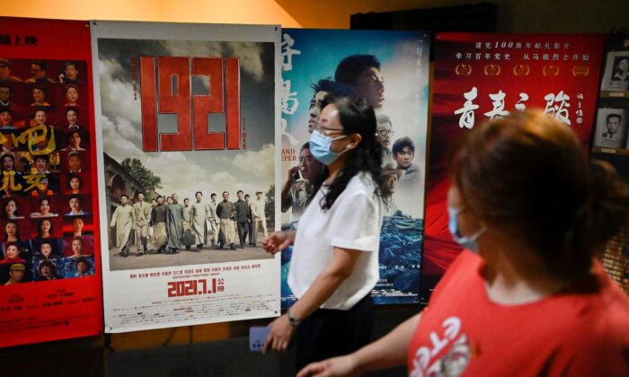 Người dân đi ngang qua một tấm bích chương quảng cáo lịch chiếu phim ‘1921’, một bộ phim tuyên truyền về sự ra đời của Đảng Cộng sản Trung Quốc cùng năm đó, trước thềm lễ kỷ niệm 100 năm thành lập Đảng Cộng sản Trung Quốc tại một rạp chiếu phim ở Bắc Kinh vào ngày 28/06/2021. (Ảnh: Wang Zhao/AFP qua Getty Images)