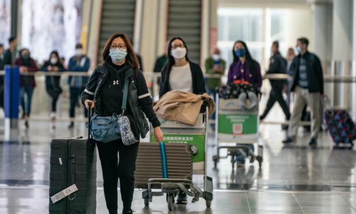 Du khách mang theo hành lý đi bộ tại sảnh đến của Phi trường Quốc tế Hồng Kông hôm 30/12/2022. (Ảnh: Anthony Kwan/Getty Images)