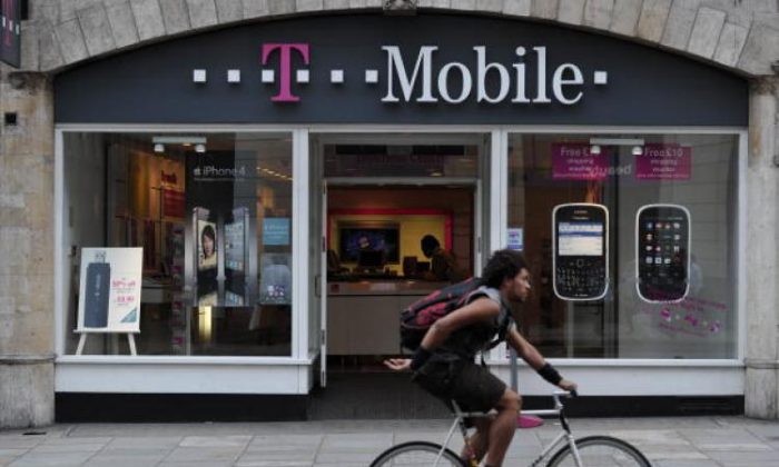 Một người đàn ông đạp xe qua cửa hàng T-Mobile ở Phố Fleet, London, Anh. Hôm Chủ nhật (15/01) AT&T Inc. đã đồng ý mua nhà mạng vô tuyến T-Mobile, trong một thỏa thuận trị giá 39 tỷ USD bằng tiền mặt và cổ phiếu. (Ảnh: Carl Court/AFP/Getty Images)