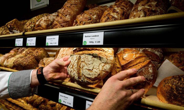 Một thợ làm bánh người Đức đặt những ổ bánh mì lên kệ trưng bày tại một tiệm bánh ở Berlin hôm 28/12/2022. (Ảnh: John Macdougall/AFP qua Getty Images)