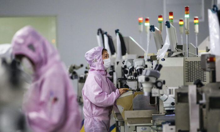 Công nhân Trung Quốc đeo khẩu trang và mặc đồ bảo hộ làm việc trên dây chuyền sản xuất vi mạch bán dẫn thông minh ở huyện Tứ Hồng (Sihong), tỉnh Giang Tô, miền đông Trung Quốc vào ngày 16/02/2020. (Ảnh: STR/AFP)