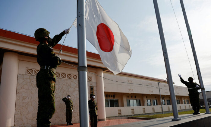 Các thành viên của Lực lượng Phòng vệ Mặt đất Nhật Bản (JGSDF) hạ quốc kỳ Nhật Bản vào đầu giờ tối, tại doanh trại quân sự Miyako trên đảo Miyako, tỉnh Okinawa, Nhật Bản, hôm 20/04/2022. (Ảnh: Issei Kato/Reuters)