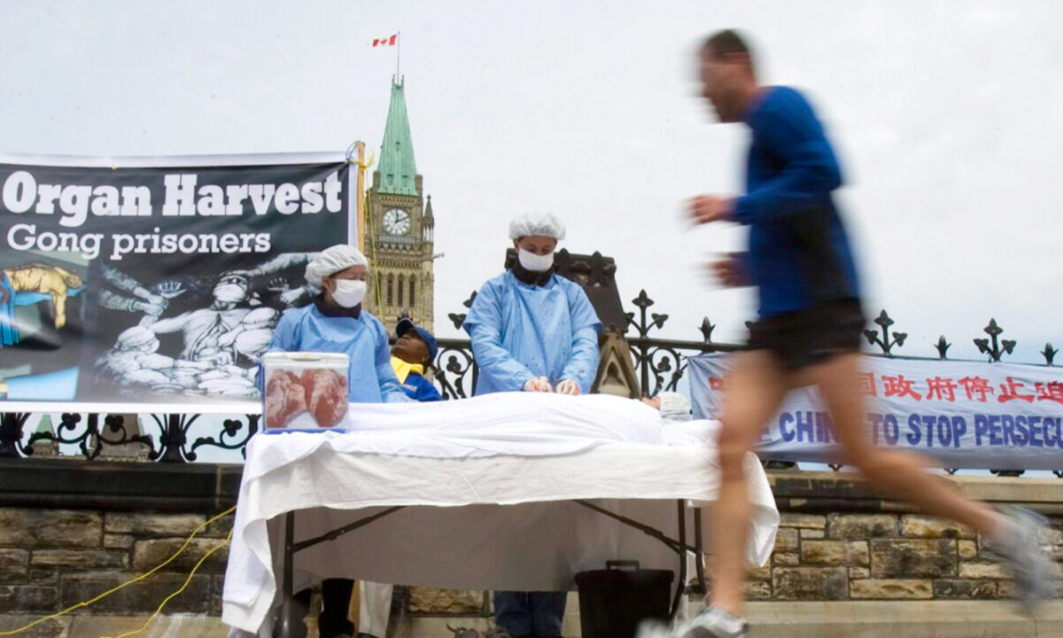 Một người đàn ông chạy ngang qua các học viên Pháp Luân Công đang mô tả lại hoạt động thu hoạch nội tạng để nâng cao nhận thức về ngành công nghiệp sát nhân lấy nội tạng trị giá hàng tỷ USD của Đảng Cộng sản Trung Quốc, trên Đồi Quốc hội ở Ottawa vào ngày 02/05/2008. (Ảnh: The Canada Press/Tom Hanson)