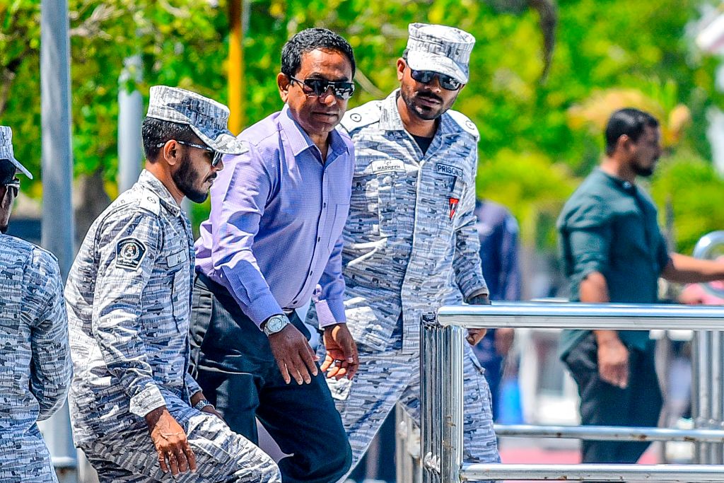 Cựu tổng thống Maldives Abdulla Yameen (Giữa) nhìn chăm chú khi ông được hộ tống lên tàu cao tốc của Dịch vụ Cải huấn để trở lại nhà tù, sau phán quyết của Tối cao Pháp viện, tại Male vào ngày 06/02/2020. – Ngày 06/02, Tòa án Tối cao Maldives ra phán quyết phản đối việc đình chỉ phán quyết và bảo lãnh tại ngoại của cựu tổng thống Abdulla Yameen, người đã bị kết án 5 năm tù vì tội rửa tiền vào ngày 28/11/2019. (Ảnh: Ahmed Shurau/AFP qua Getty Images)