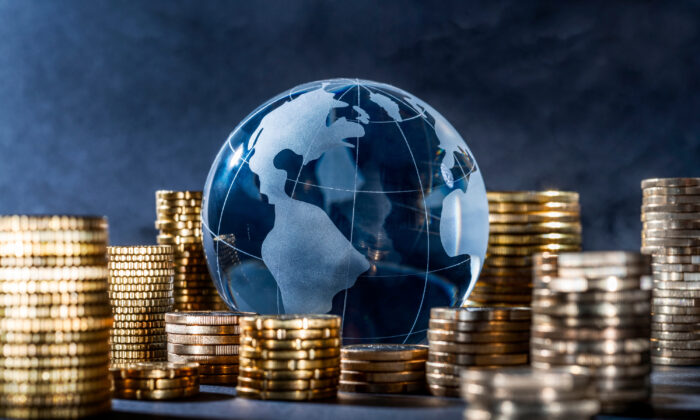 Quả địa cầu và chồng tiền xu. Đồng tiền làm cho thế giới xoay tròn. (Ảnh: gopixa/Shutterstock)