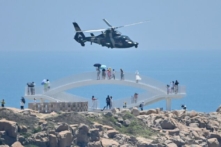 Các du khách ngắm nhìn một trực thăng quân sự Trung Quốc bay qua đảo Bình Đàm, một trong những điểm gần nhất của Hoa lục với Đài Loan, ở tỉnh Phúc Kiến, vào ngày 04/08/2022. (Ảnh: Hector Retamal/AFP qua Getty Images)