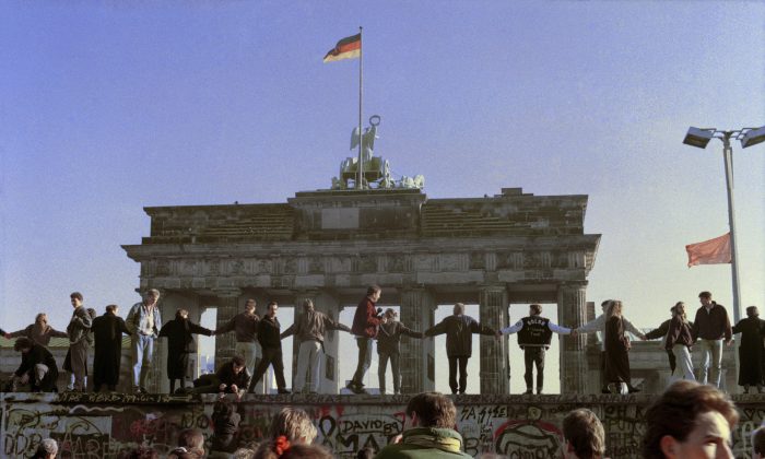 Bức ảnh tư liệu ngày 10/11/1989 này cho thấy người dân Berlin đang ca hát và nhảy múa trên đỉnh Bức tường Berlin để ăn mừng ngày mở cửa biên giới Đông Đức-Tây Đức. (Ảnh: AP Photo/Thomas Kienzle)