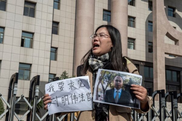 Bà Hứa Diễm (Xu Yan), vợ của luật sư nhân quyền Dư Văn Sinh (Yu Wensheng), cầm một mảnh giấy có nội dung “Tôi muốn gặp Thẩm phán Lưu Minh Vĩ” và một bức ảnh của người chồng lúc đó đang bị giam giữ bên ngoài Tòa án Nhân dân Trung cấp Từ Châu ở Từ Châu, Trung Quốc, vào ngày 31/10/2019. (Ảnh: Nicolas Asfouri/AFP qua Getty Images)