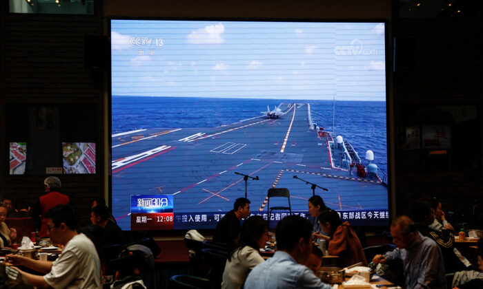 Thực khách dùng bữa gần một màn hình tin tức lớn chiếu cảnh phi cơ thuộc Bộ Tư lệnh Chiến khu Đông bộ của Quân Giải phóng Nhân dân Trung Quốc (PLA) tham gia một cuộc tập trận tuần tra sẵn sàng chiến đấu và cuộc tập trận mang tên “Kiếm sắc Liên hợp” xung quanh đảo Đài Loan, tại một nhà hàng ở Bắc Kinh, Trung Quốc, hôm 10/04/2023. (Ảnh: Tingshu Wang/Reuters)