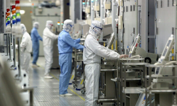 Các kỹ thuật viên đang làm việc trong phòng sạch với thiết bị sản xuất chất bán dẫn (FAB) của hãng Fab Equipment tại một công ty bán dẫn tên là Renesas Technology Corp., ở Ibaraki, Nhật Bản, vào ngày 17/06/2004. (Ảnh: Koichi Kamoshida/Getty Images)