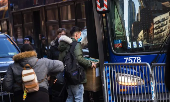 Những người nhập cư bất hợp pháp mang đồ đạc của họ lên một chiếc xe buýt sau khi đồng ý di dời sau khi bị trục xuất khỏi khách sạn Watson ở thành phố New York hôm 30/01/2023. (Ảnh: Michael M. Santiago/Getty Images)