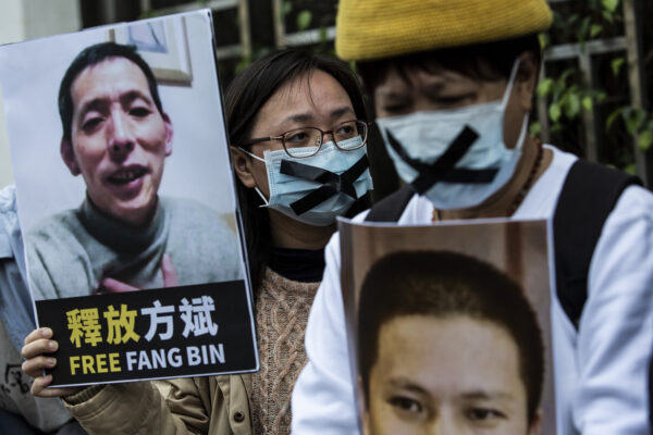 Một nhà hoạt động dân chủ (giữa) từ nhóm HK Alliance cầm một tấm bảng ghi tên ký giả công dân bị mất tích Phương Bân, khi cô biểu tình bên ngoài văn phòng liên lạc Trung Quốc ở Hồng Kông vào ngày 19/02/2020. (Ảnh: Isaac Lawrence/AFP qua Getty Images)
