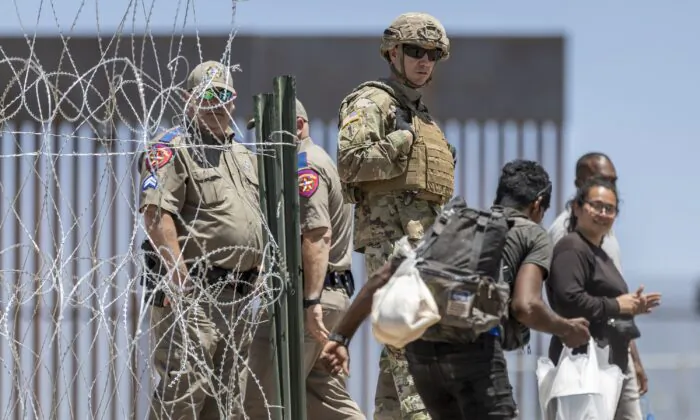 Một binh sĩ của Lực lượng Vệ binh Quốc gia Texas quan sát một người di cư bước vào khu trại tạm thời dành cho người di cư ở El Paso, Texas hôm 11/05/2023. (Ảnh: John Moore/Getty Images)