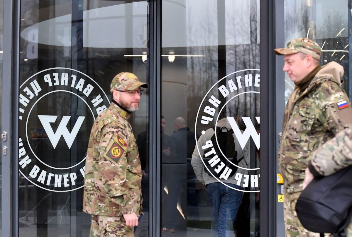 Hai vị khách mặc đồ rằn ri quân đội đứng ở lối vào của “Trung tâm PMC Wagner,” liên kết với lãnh đạo Yevgeny Prigozhin của tập đoàn quân sự tư nhân (PMC) Wagner, trong lễ khai trương chính thức tòa nhà văn phòng ở St. Petersburg, Nga, vào ngày 04/11/2022. (Ảnh: Olga Maltseva/AFP qua Getty Images)