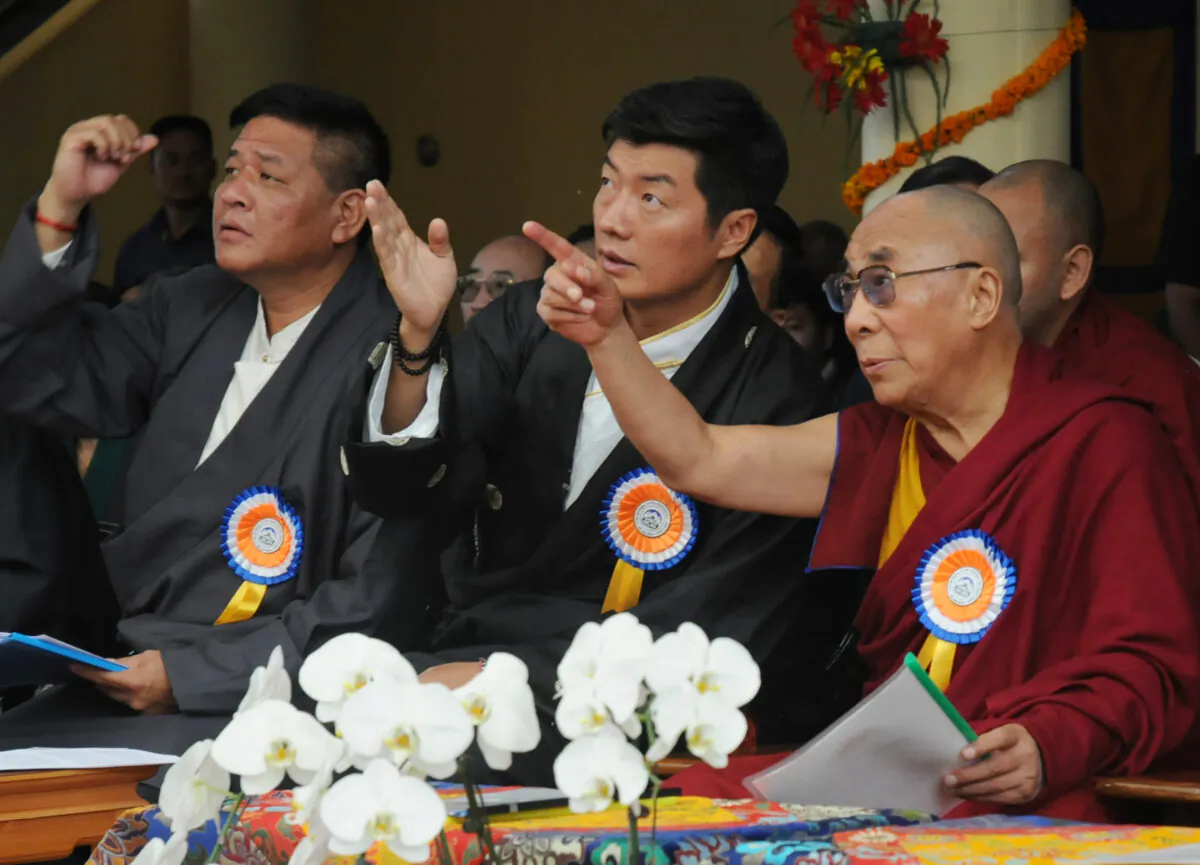 Nhà lãnh đạo tinh thần của Tây Tạng Đức Đạt Lai Lạt Ma (Phải), Thủ tướng Tây Tạng lưu vong Lobsang Sangay (Giữa), và Chủ tịch Quốc hội Tây Tạng lưu vong Penpa Tsering (Trái) ra hiệu bằng tay trước một biểu ngữ có hình Đức Đạt Lai Lạt Ma ở các độ tuổi khác nhau trong lễ kỷ niệm sinh nhật lần thứ 77 của ông tại Chùa Tsuglakhang ở McLeod Ganj, Dharamsala, vào ngày 06/07/2012. Nhà lãnh đạo Tây Tạng này, đã đào thoát khỏi quê hương đến miền bắc Ấn Độ vào năm 1959 sau một cuộc nổi dậy thất bại phản đối sự cai trị của cộng sản Trung Quốc, năm 2011 tuyên bố rằng ông sẽ từ bỏ vai trò chính trị của mình để tập trung vào các nghĩa vụ tinh thần. (Ảnh: STDEL/AFP/GettyImages)