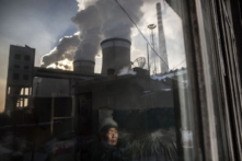 Một cư dân Trung Quốc nhìn ra cửa sổ ngôi nhà của mình bên cạnh một nhà máy nhiệt điện than ở tỉnh Sơn Tây, Trung Quốc, vào ngày 26/11/2015. (Ảnh: Kevin Frayer/Getty Images)