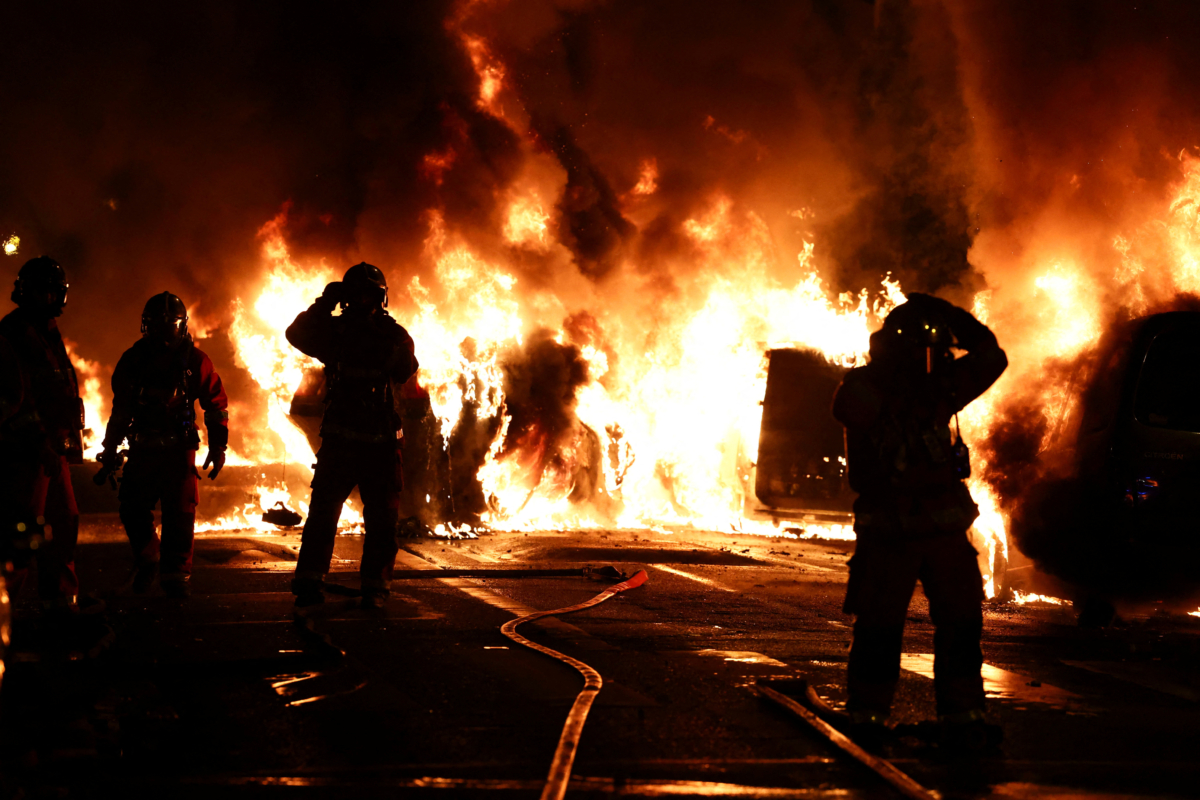 Nhân viên cứu hỏa đứng yên khi họ dập tắt các xe đang bốc cháy trong cuộc đụng độ giữa người biểu tình và cảnh sát, sau khi một thiếu niên 17 tuổi bị cảnh sát Pháp bắn tử vong trong lúc dừng giao thông ở Nanterre, ngoại ô Paris, Pháp, hôm 28/06/2023. (Ảnh: Reuters/Stephanie Lecocq)