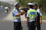 Cảnh sát Trung Quốc bắt giữ một ký giả tại một trạm kiểm soát trên đường đến thị trấn Lukqun, vùng Tân Cương, nơi bị ảnh hưởng bởi bạo loạn của người Duy Ngô Nhĩ, vào ngày 28/06/2013. (Ảnh: Mark Ralston/AFP qua Getty Images)