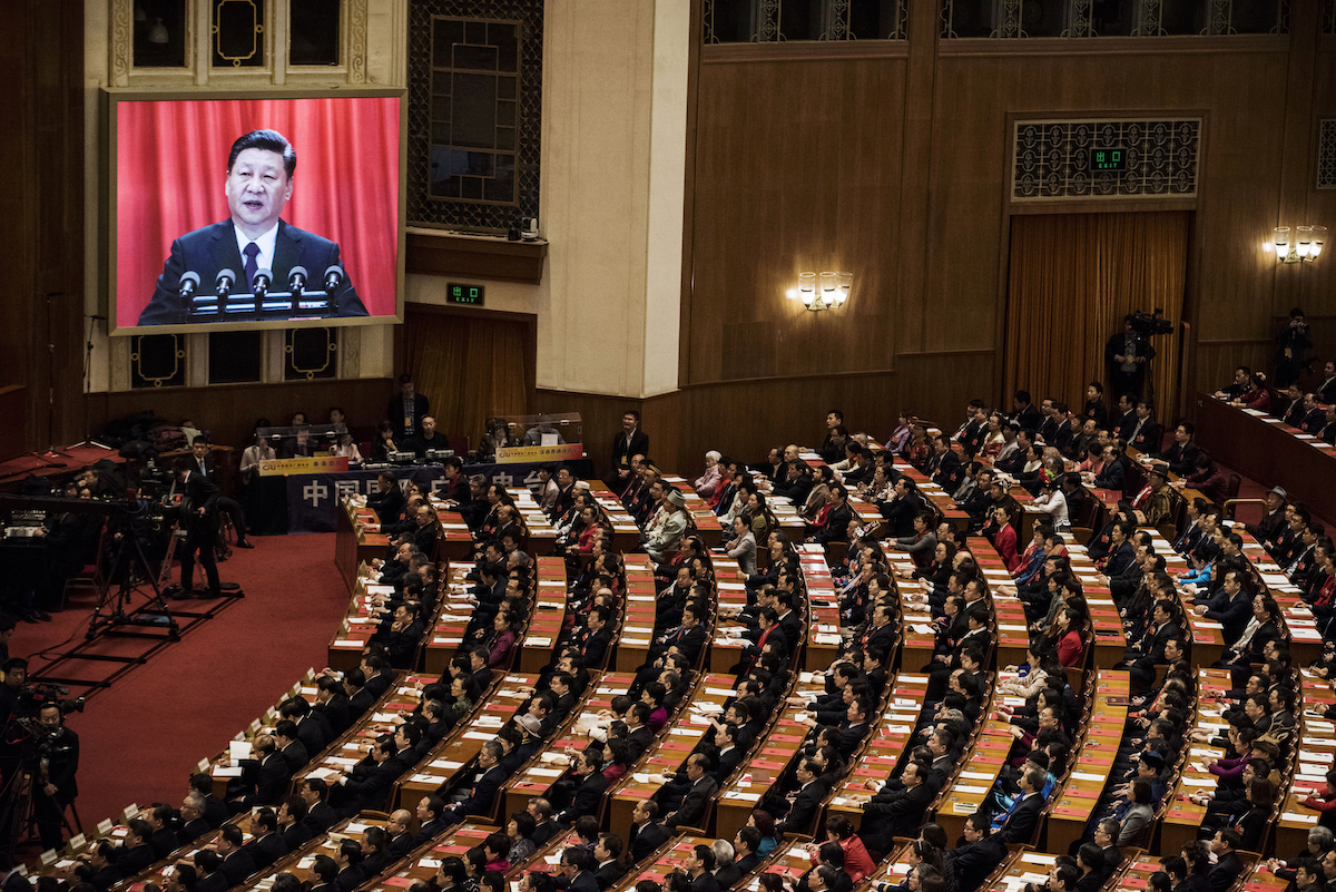 Các đại biểu lắng nghe bài diễn văn của lãnh đạo Trung Quốc Tập Cận Bình khi ông xuất hiện trên màn hình lớn trong phiên bế mạc của Đại hội Đại biểu Nhân dân Toàn quốc tại Đại lễ đường Nhân dân ở Bắc Kinh, vào ngày 20/03/2018. (Ảnh: Kevin Frayer/Getty Images)