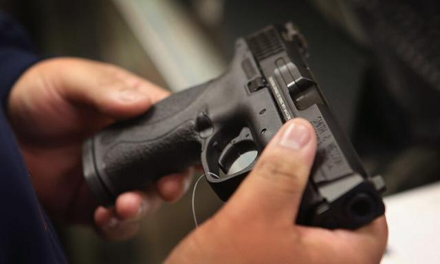 Một khách hàng mua một khẩu súng lục tại cửa hàng đồ thể thao Freddie Bear Sports ở Tinley Park, Illinois, vào ngày 17/12/2012. (Ảnh: Scott Olson/Getty Images)