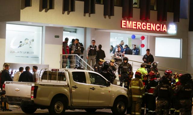 Đứng bao quanh một chiếc xe bị bắn thủng lỗ chỗ là những cảnh sát đang bảo vệ bệnh viện nơi một số người bị thương được đưa đến sau vụ tấn công ứng cử viên tổng thống Fernando Villavicencio, người bị bắn đến tử vong ở Quito, Ecuador, hôm 09/08/2023. (Ảnh: AP Photo/Juan Diego Montenegro)