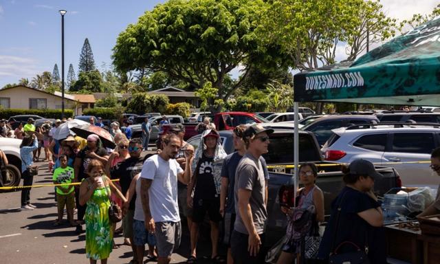 Người dân xếp hàng chờ nhận bữa ăn miễn phí tại một trung tâm phân phát cho những người bị đám cháy Maui ảnh hưởng tại Công viên Bãi biển Honokawai ở Napili-Honokowai, Tây Maui, Hawaii hôm 14/08/2023. (Ảnh: Yuki Iwamura/AFP qua Getty Images)