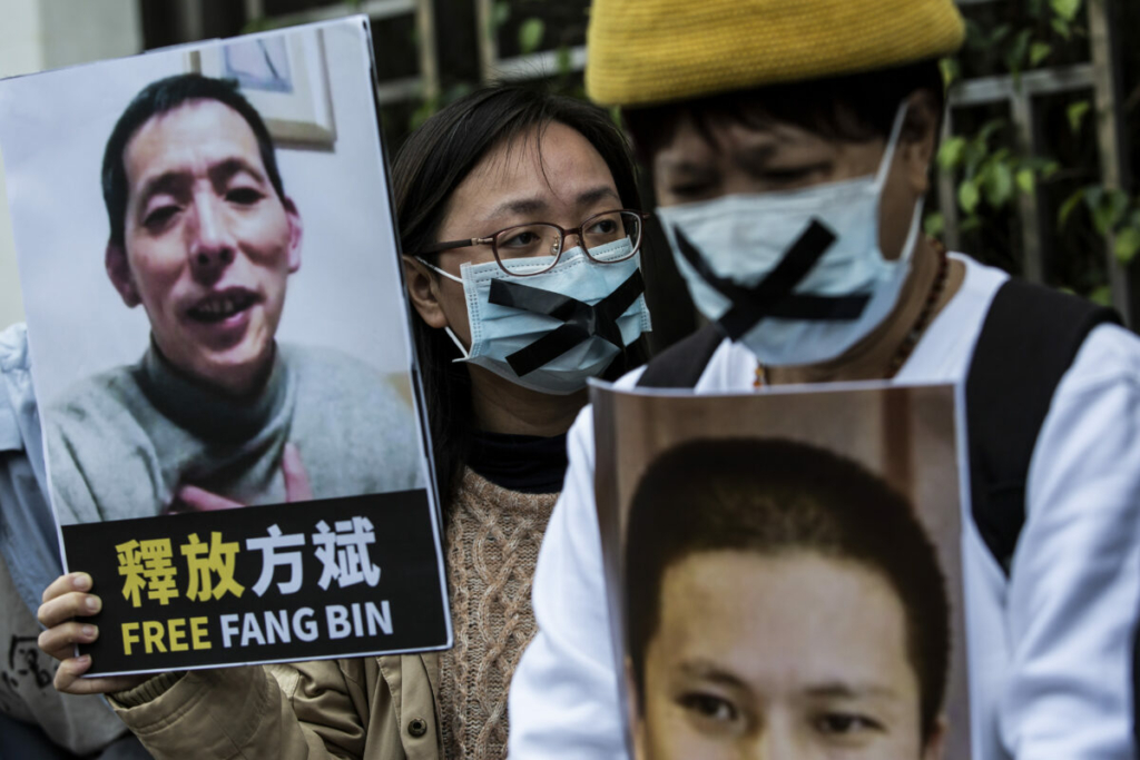 Một nhà hoạt động ủng hộ dân chủ (ở giữa) từ Liên minh Hồng Kông cầm tấm bảng có hình ký giả công dân mất tích Phương Bân (Fang Bin), khi cô biểu tình bên ngoài văn phòng liên lạc Trung Quốc ở Hồng Kông vào ngày 19/02/2020. (Ảnh: Isaac Lawrence/AFP qua Getty Images)