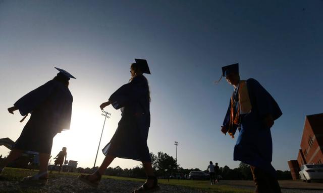 Các học sinh cuối cấp trung học tiến đến sân bóng khi mặt trời bắt đầu lặn để dự lễ tốt nghiệp ở Saltillo, Mississippi, vào ngày 27/06/2020. (Ảnh: Thomas Wells/Nhật báo The Northeast Mississippi qua AP, Tư liệu)