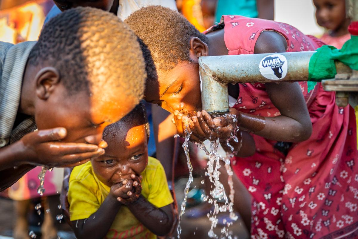 Trẻ em thưởng thức từng ngụm nước sạch tại một vòi nước giếng do tổ chức Water Wells for Africa (Giếng Nước Cho Châu Phi) xây dựng ở Làng Maggie B, Malawi, vào ngày 30/06/2021. (Ảnh: John Fredricks/The Epoch Times)